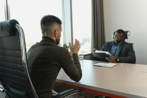 2 business men talking at desk.