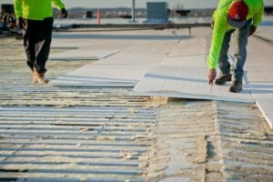 a roofer cutting into commercial roofing insulation.